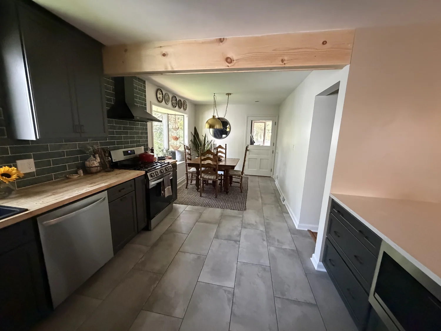 Remodeled kitchen after wall removal with a broad opening toward the dining room and butcher-block work surface