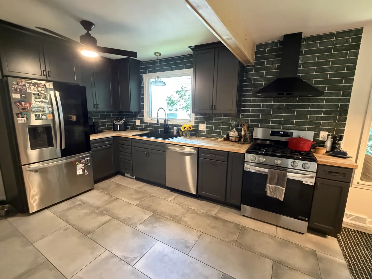 Completed Mayfield Heights kitchen from the sink-wall angle with deep-toned cabinetry, butcher-block counters, marble backsplash, and tile flooring