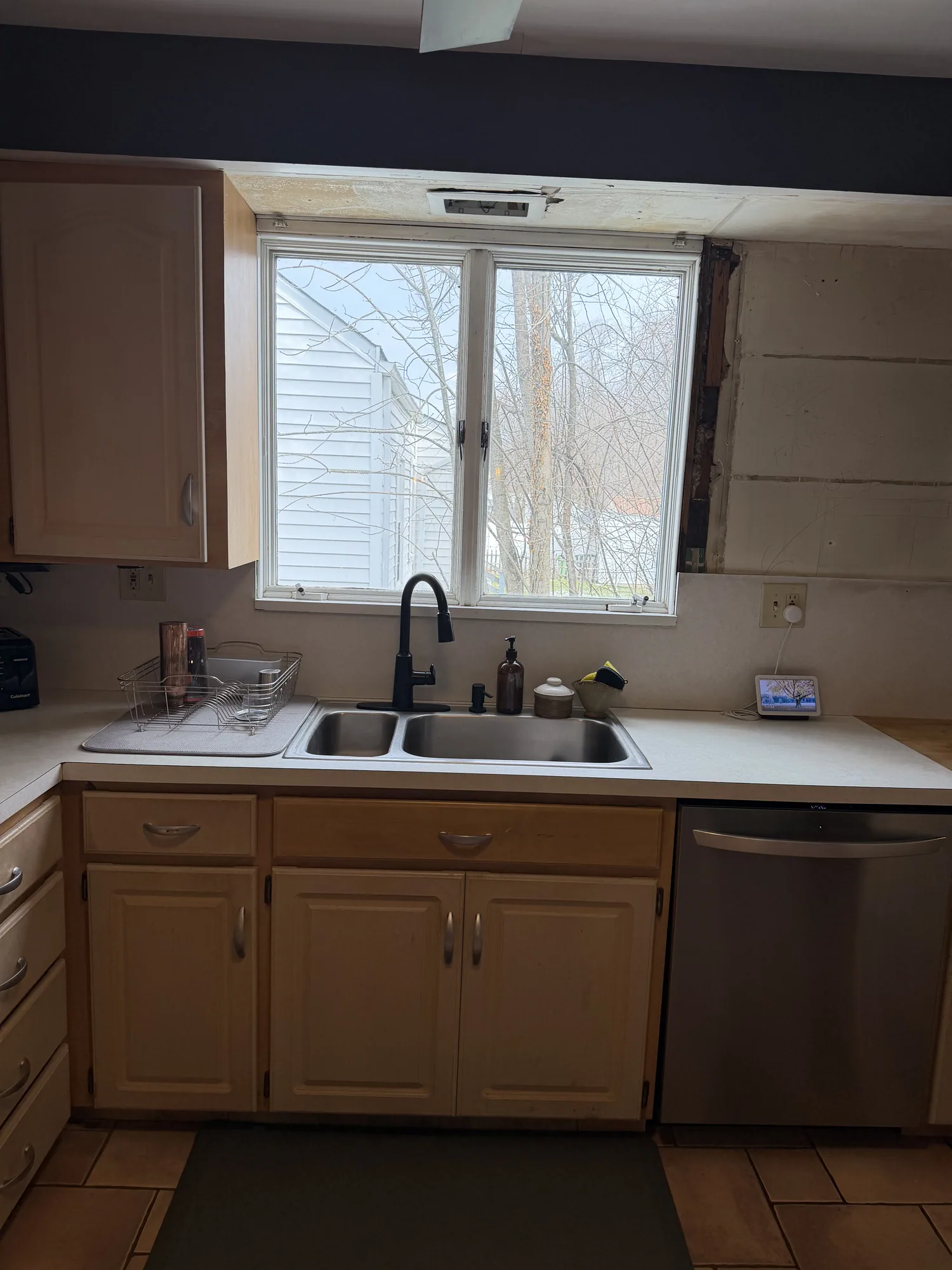 Original kitchen sink wall with light wood cabinets and white laminate countertop
